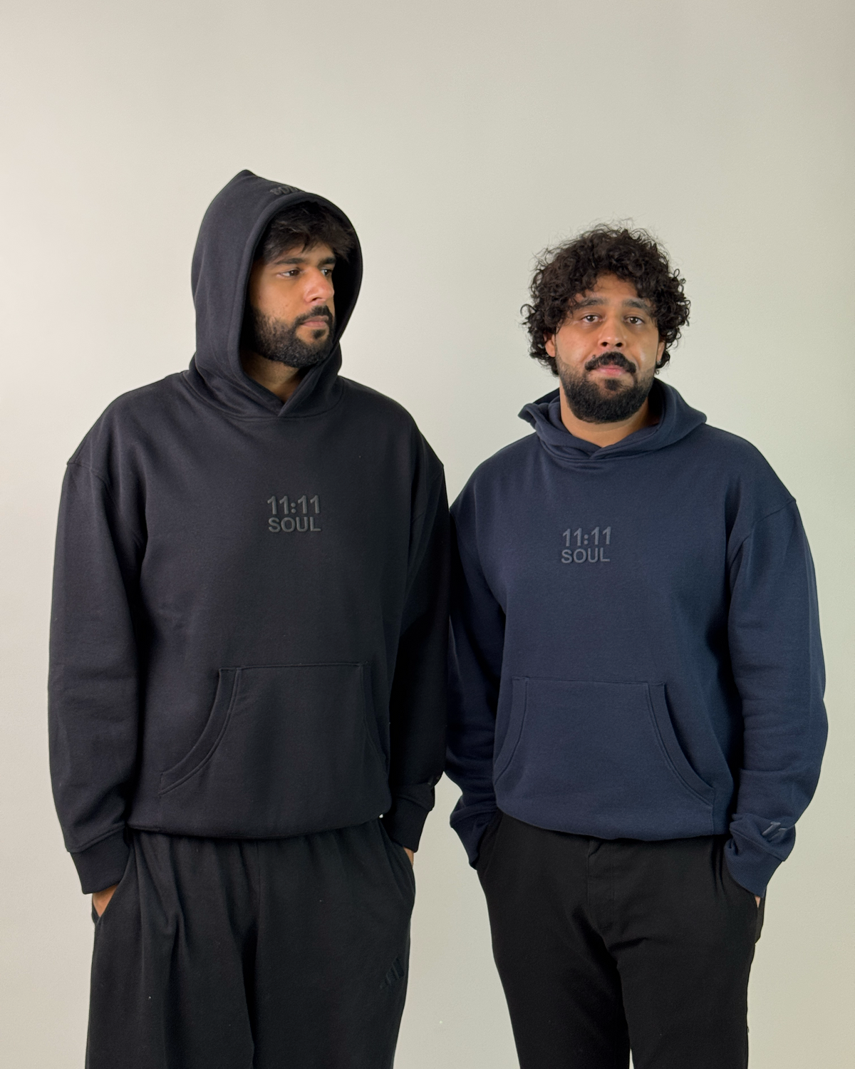 Two men wearing matching navy and black hoodies with a small white 'BAIL' logo on the chest, posed against a plain light background.